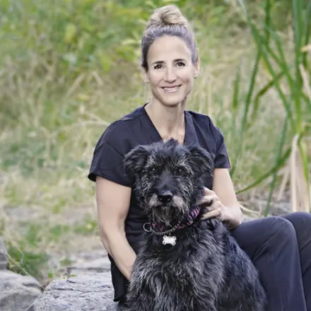 Dr. Jennifer Watt sitting with a black dog outside